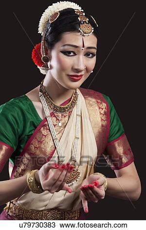 Stock Image - Portrait of beautiful dancer performing Bharatanatyam over black background. Fotosearch