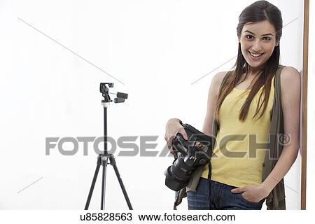 Portrait of beautiful young photographer with digital camera leaning against wall View Large Photo Image Stock Image - Portrait of beautiful young photographer with digital camera leaning against wall . Fotosearch