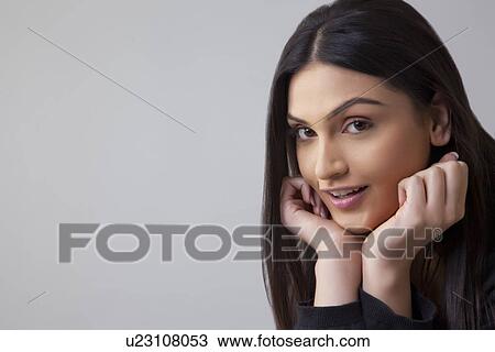 Portrait of beautiful young woman with hand on chin isolated over colored background View Large Photo Image Stock Image - Portrait of beautiful young woman with hand on chin isolated over colored background . Fotosearch
