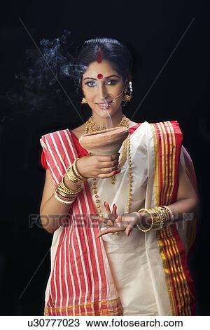 Stock Image - Portrait of Bengali woman holding a dhunuchi. Fotosearch