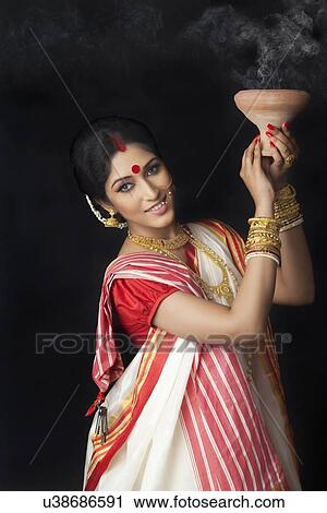 Stock Image - Portrait of Bengali woman holding a dhunuchi. Fotosearch