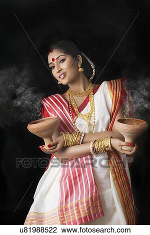 Stock Image - Portrait of Bengali woman holding dhunuchis. Fotosearch
