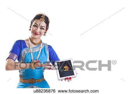 Stock Photograph - Portrait of Bharatanatyam dancer listening music on digital tablet over white background. Fotosearch