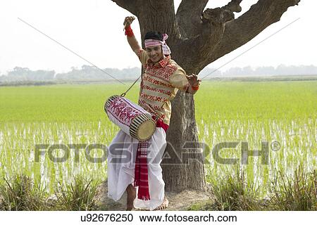 Stock Image - Portrait of Bihu man playing on a dhol . Fotosearch