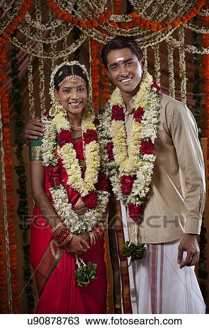 Stock Image - Portrait of bride and groom wearing garlands during traditional Indian wedding . Fotosearch