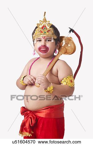 Stock Image - Portrait of confident boy dressed as Lord Hanuman against white background. Fotosearch