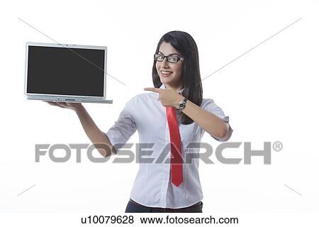 Stock Photo - Portrait of confident businesswoman pointing at laptop over white background. Fotosearch