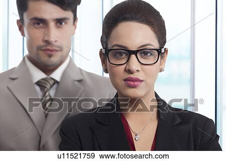 Stock Photo - Portrait of confident businesswoman with colleague in office. Fotosearch