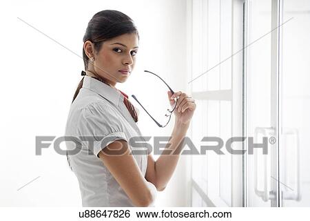 Portrait of confident businesswoman holding glasses with pride View Large Photo Image Stock Photograph - Portrait of confident businesswoman holding glasses with pride . Fotosearch