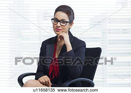 Portrait of confident businesswoman sitting in office View Large Photo Image Stock Photography - Portrait of confident businesswoman sitting in office. Fotosearch