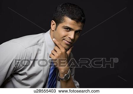 Stock Image - Portrait of confident male executive over black background . Fotosearch