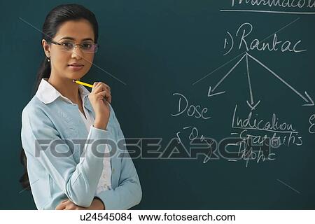 Portrait of confident young teacher against green board View Large Photo Image Picture - Portrait of confident young teacher against green board . Fotosearch