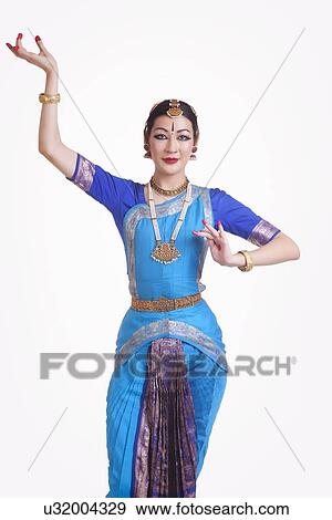 Portrait of confident young woman performing Bharatanatyam over white background View Large Photo Image Stock Photo - Portrait of confident young woman performing Bharatanatyam over white background. Fotosearch