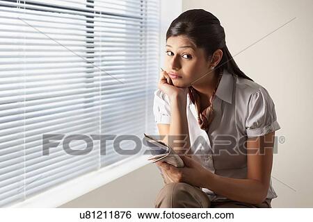 Stock Photograph - Portrait of confused businesswoman while solving puzzle at office . Fotosearch