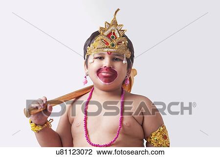 Stock Image - Portrait of cute boy dressed as God Hanuman against white background. Fotosearch