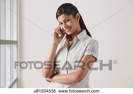 Stock Photography - Portrait of cute young business woman on phone call at officePortrait of cute young business woman on phone call at office . Fotosearch