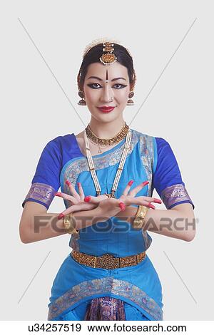 Stock Photo - Portrait of dancer gesturing while performing Bharatanatyam against white background. Fotosearch