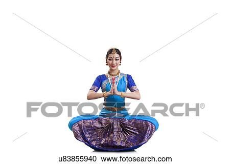 Stock Image - Portrait of dancer greeting while performing Bharatanatyam against white background. Fotosearch