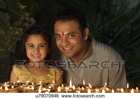 Stock Photograph - Portrait of father and daughter with diyas . Fotosearch