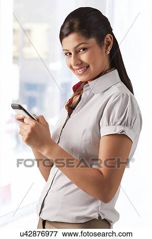 Stock Photo - Portrait of female professional text messaging on cell phone . Fotosearch