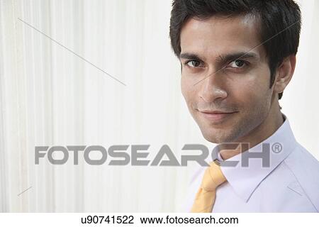 Portrait of good looking businessman smiling in office View Large Photo Image Stock Image - Portrait of good looking businessman smiling in office . Fotosearch