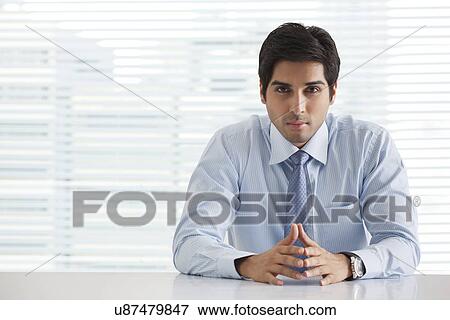 Stock Photo - Portrait of handsome young businessman sitting in office . Fotosearch