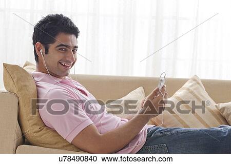 Portrait of handsome young man relaxing while listening to music View Large Photo Image Stock Image - Portrait of handsome young man relaxing while listening to music . Fotosearch