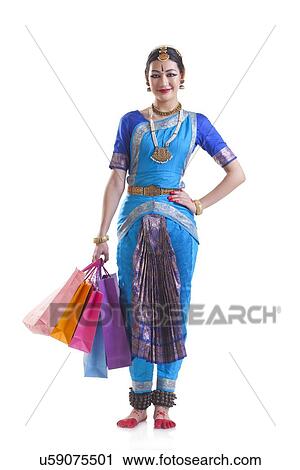 Portrait of happy Bharatanatyam dancer carrying shopping bags over white background View Large Photo Image Stock Image - Portrait of happy Bharatanatyam dancer carrying shopping bags over white background. Fotosearch