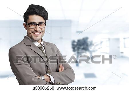 Portrait of happy businessman standing arms crossed in office View Large Photo Image Stock Photo - Portrait of happy businessman standing arms crossed in office. Fotosearch