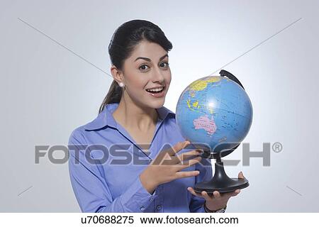 Portrait of happy businesswoman holding globe against gray background View Large Photo Image Stock Photography - Portrait of happy businesswoman holding globe against gray background. Fotosearch