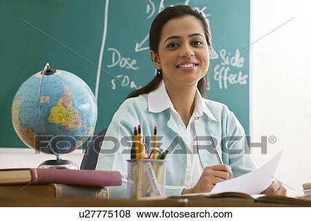 Portrait of happy female teacher at desk View Large Photo Image Stock Photo - Portrait of happy female teacher at desk . Fotosearch