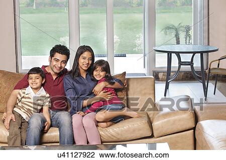 Portrait of happy Indian family of four sitting together on sofa View Large Photo Image Stock Image - Portrait of happy Indian family of four sitting together on sofa . Fotosearch