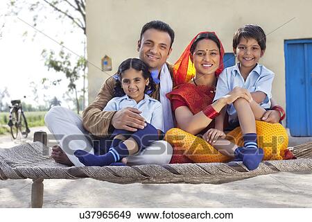 Stock Photo - Portrait of happy rural Indian family sitting on cot . Fotosearch