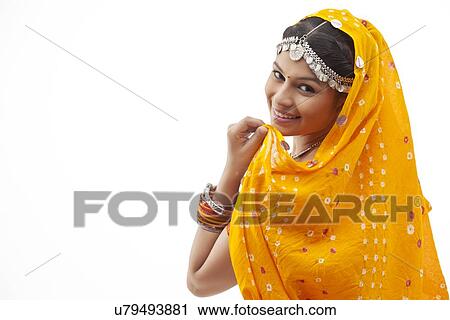 Stock Image - Portrait of happy shy woman in traditional clothing looking over shoulder against white background. Fotosearch