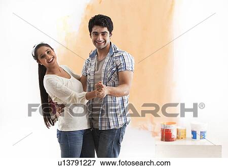 Stock Photo - Portrait of happy young couple dancing together at their new home . Fotosearch