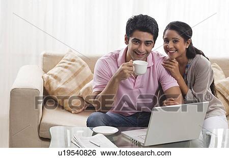 Portrait of happy young couple smiling with laptop and coffee cup View Large Photo Image Stock Photograph - Portrait of happy young couple smiling with laptop and coffee cup . Fotosearch