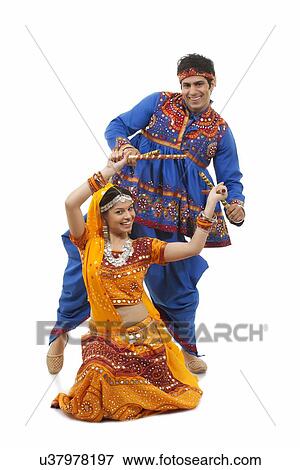 Portrait of happy young Indian couple performing Dandiya Raas over white background View Large Photo Image Stock Photo - Portrait of happy young Indian couple performing Dandiya Raas over white background. Fotosearch