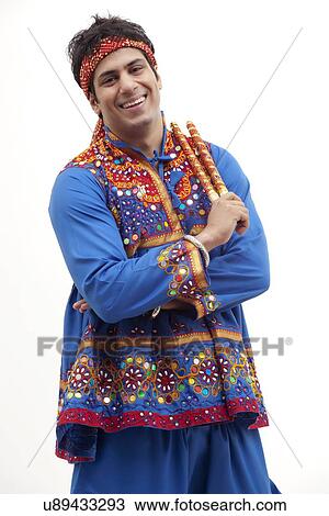 Portrait of happy young man in kedia holding dandiyas over white background View Large Photo Image Stock Image - Portrait of happy young man in kedia holding dandiyas over white background. Fotosearch