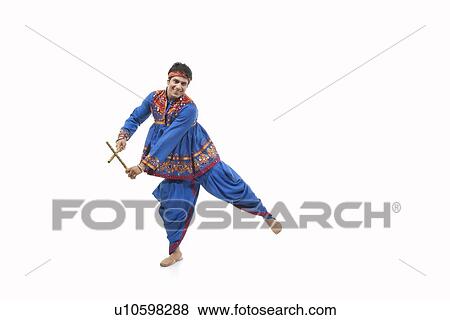 Stock Photo - Portrait of happy young man in traditional wear performing Dandiya Rass over white background. Fotosearch