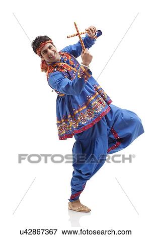 Stock Photo - Portrait of happy young man in traditional wear performing Dandiya Rass over white background. Fotosearch