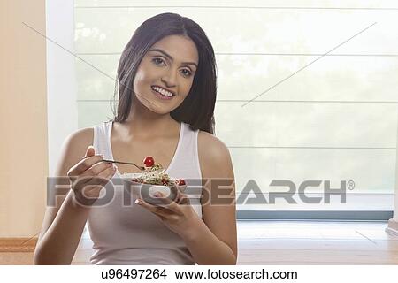 Portrait of happy young woman eating bean sprouts and cherry tomatoes View Large Photo Image Picture - Portrait of happy young woman eating bean sprouts and cherry tomatoes . Fotosearch