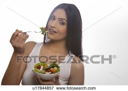 Stock Photo - Portrait of happy young woman eating salad of lettuce, cherry tomatoes and mushrooms . Fotosearch