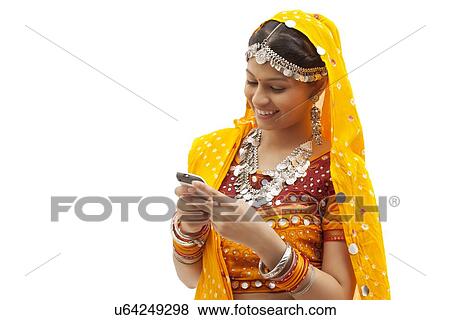 Portrait of happy young woman in traditional wear messaging on cell phone against white background View Large Photo Image Stock Photo - Portrait of happy young woman in traditional wear messaging on cell phone against white background. Fotosearch