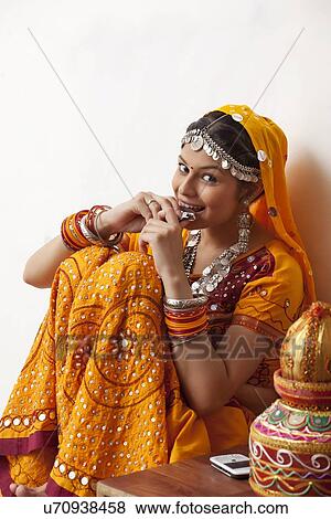 Portrait of happy young woman in chaniya choli eating chocolate against white background View Large Photo Image Stock Photo - Portrait of happy young woman in chaniya choli eating chocolate against white background. Fotosearch