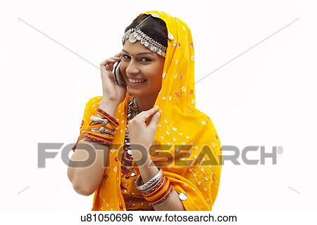 Portrait of happy young woman in traditional wear using cell phone over white background View Large Photo Image Stock Photograph - Portrait of happy young woman in traditional wear using cell phone over white background. Fotosearch