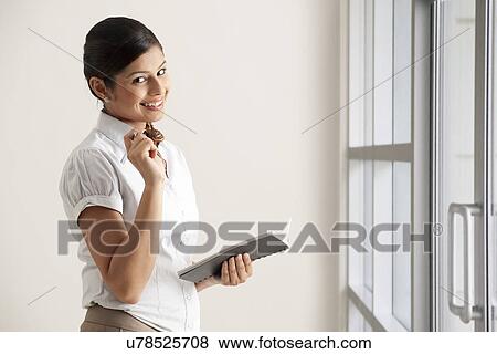 Stock Photo - Portrait of Indian businesswoman smiling while holding diary . Fotosearch