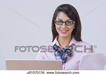 Picture - Portrait of Indian businesswoman with laptop and document at office. Fotosearch