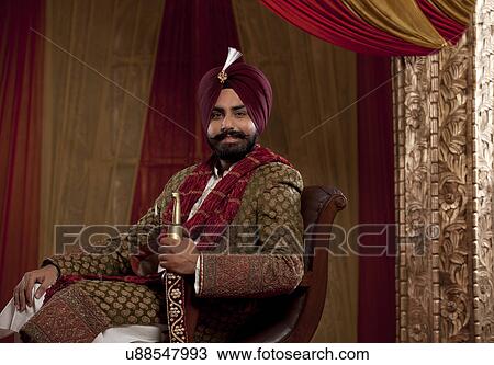 Stock Image - Portrait of Indian ethnicity mid adult man sitting on chair. . Fotosearch