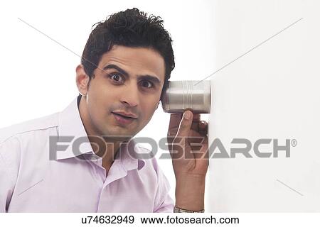 Portrait of man holding glass against wall listening View Large Photo Image Stock Photo - Portrait of man holding glass against wall listening. Fotosearch