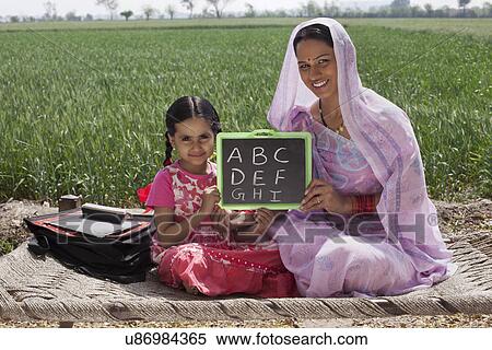 Portrait of mother and daughter holding a writing slate with alphabets written on it View Large Photo Image Stock Photography - Portrait of mother and daughter holding a writing slate with alphabets written on it . Fotosearch